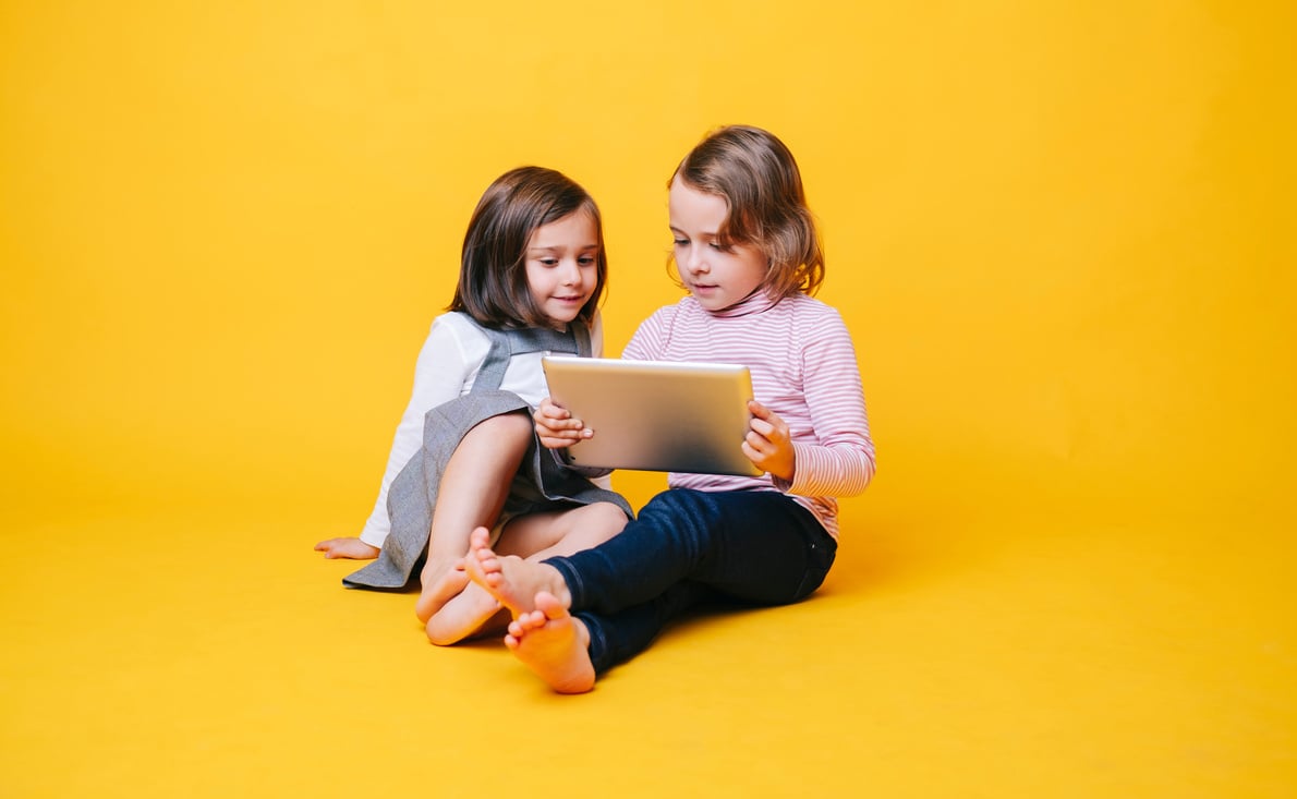 Two Kids with Tablet  on Yellow Background